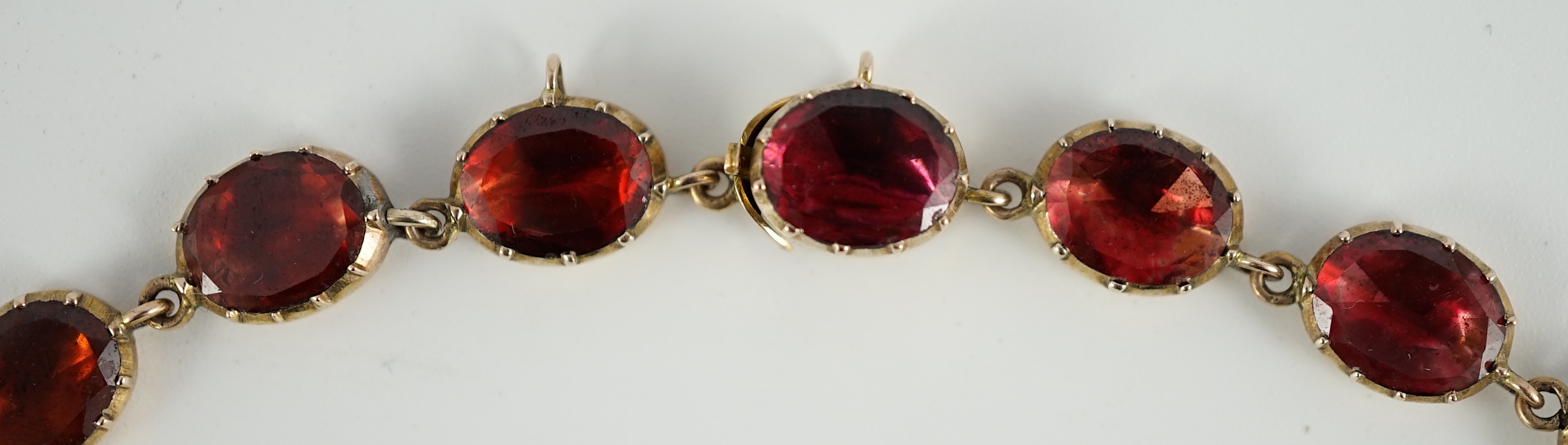 An early 19th century gold mounted graduated foil backed oval cut garnet set choker necklace